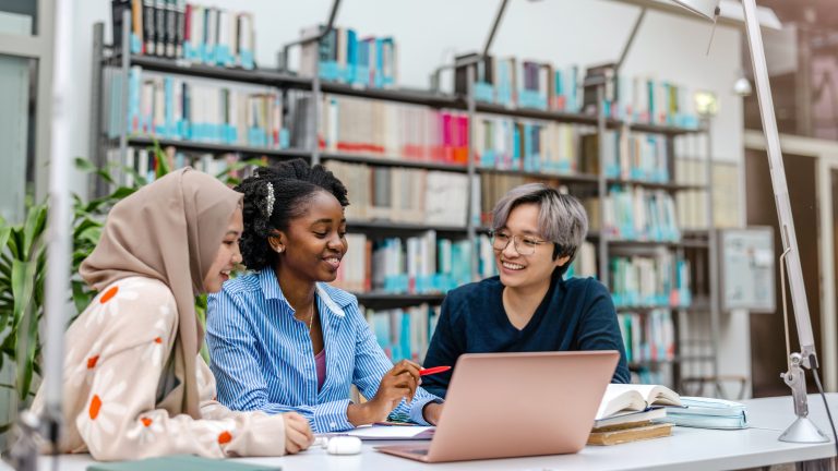 Multiethnic group of students sitting in alibrary and studying together