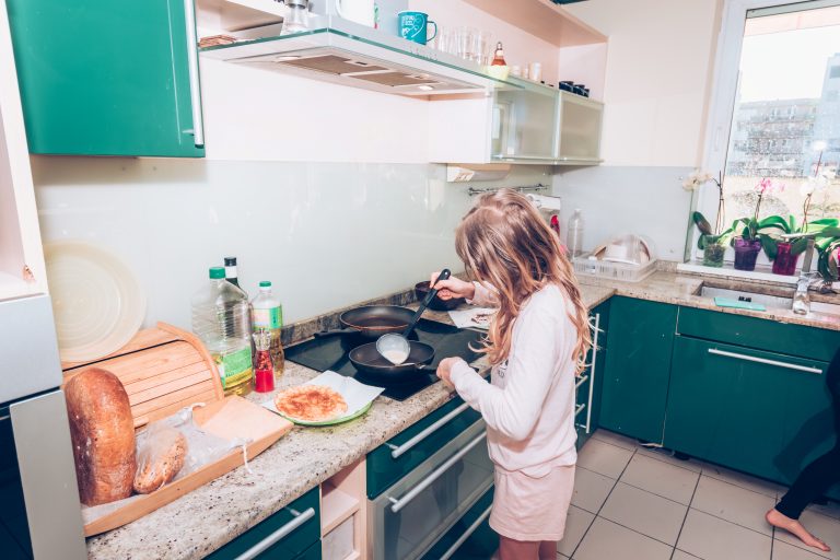 young teenage child cooking alone in the kitchen